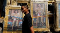 Seorang pria melintas di depan foto Putra Mahkota Maha Vajiralongkorn. REUTERS/Jorge Silva.