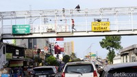 Seorang warga melintas di JPO yang sedang diperbaiki.