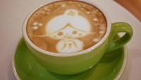 Dalam gelas keramik berwarna hijau, tersaji latte art berkarawkter lucu dengan foam lembut. Slurp, perpaduan kopi espresso serta susunya beradu seimbang.