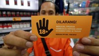 Pekerja minimarket menunjukkan stiker larangan menjual rokok kepada anak dibawah usia 18 tahun.