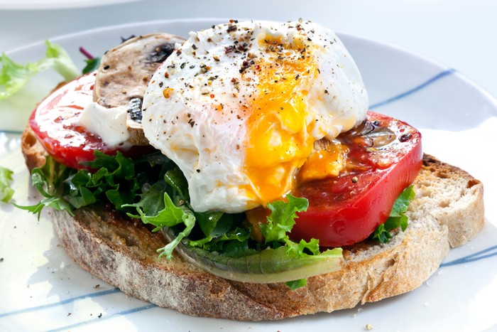 telur Poached egg on sourdough toast, with grilled tomatoes, mushrooms and salad leaves. A healthy, delicious breakfast or brunch.