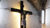 Salib Yesus yang berada di sisi lain gereja. Setting lampu yang dramatis kian membuat suasana kian sakral. Umat pun ada yang memegang kakinya sebagai simbol (Rachman/detikTravel)