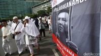 Sejumlah peserta aksi melintas di depan spanduk Ahok yang dipasanga di kawasan Bundaran HI, Jumat (2/12/2016).