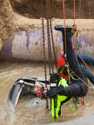 Petugas berusaha mengevakuasi mobil yang jatuh ke dalam lubang 