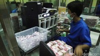 Seorang karyawan tengah merapikan uang kertas.