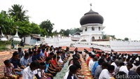 Di latar belakangnya, tampak masjid yang telah roboh dan menyisakan kubah masjid saja.