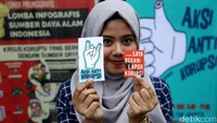 Seorang pengunjung menunjukan stiker anti korupsi.