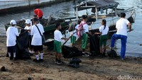 Para siswa membersihkan sampah di darat dan lautan.