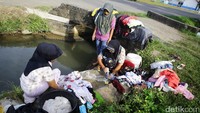 Fitriyani (41) bersama Yusnidar (35) dan Ulfa (17) mencuci pakaian di parit di Jalan Tgk Syik Pante Geulima, Pidie Jaya.