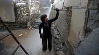 Marjan Teeuwen tengah mengikis sebuah tembok di salah satu reruntuhan rumah belum lama ini di Khan Younis, Jalur Gaza Selatan, Palestina. REUTERS/Ibraheem Abu Mustafa.