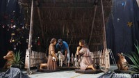 Petugas sedang menyusun pernak-pernik kandang Natal.