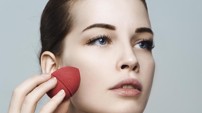 Beautiful woman face. Perfect makeup. Skincare foundation. Sponge makeup artist