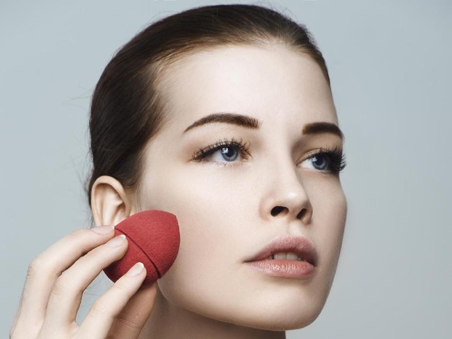 Beautiful woman face. Perfect makeup. Skincare foundation. Sponge makeup artist