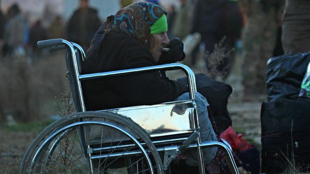 Warga Aleppo yang telah dievakuasi terduduk di kursi roda sambil makan