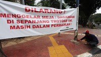 Seorang pekerja sedang mengecek trotoar yang sedang dalam perbaikan.