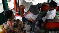 Petugas membagikan poster kepada penumpang bus.