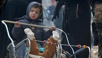 Seorang anak bermain dengan adiknya yang berada di kereta bayi. REUTERS/Abdalrhman Ismail.
