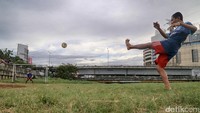 Warga memanfaatkan endapan lumpur kering di bibir Sungai Kanal Banjir Barat untuk bermain bola, di kawasan Roxy, Jakarta, Senin (19/12/2016).