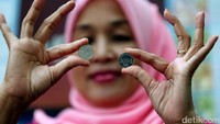 Usai mengantre, seorang warga memamerkan uang logam baru pecahan Rp 1.000.