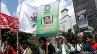 Massa membawa atribut aksi seperti bendera dan poster.