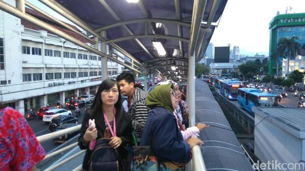 Warga melihat aksi pria pemanjat baliho di Harmoni, Jakarta Pusat, Selasa (20/12/2016)