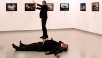 Pelaku yang berdiri di samping Andrey Karlov menodongkan pistolnya ke arah pengunjung. Stringer/AFP.