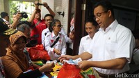 Cagub Anies Baswedan melayani pembeli dalam kampanye pasar sembako murah.