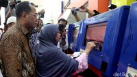 Budi Karya Sumadi melihat calon penumpang yang sedang mencetak tiket di mesin cetak online.