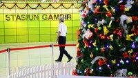Seorang pria tengah melintas di depan pohon Natal di salah satu sudut Stasiun Gambir.