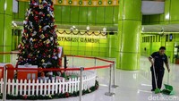 Seorang petugas kebersihan tengah menyapu di sekitar pohon Natal.