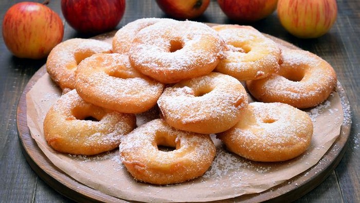 Pile of mini powdered sugar donuts against a white background