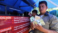 Seorang warga memamerkan uang rupiah desain baru usai antre di halaman parkir Gedung DPR, Senayan, Jakarta, Jumat (23/12/2016).