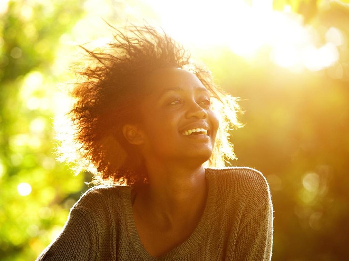 Close up portrait of a beautiful african american woman smiling with sunset