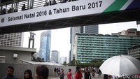 Beberapa warga melintas di bawah jembatan bertuliskan Selamat Natal & Tahun Baru 2017.