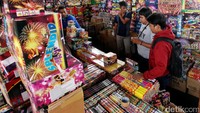 Pedagang kembang api melayani beberapa pembeli.