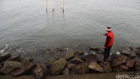 Seorang warga tengah memancing di kawasan pelabuhan Muara Baru.