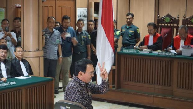 Ahok tersenyum dan berpose salam dua jari.