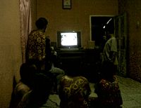 Keluarga Emi dan Santi berkumpul memantau perkembangan kasus Pembunuhan di Pulomas melalui televisi.