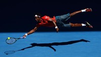 Gael Monfils melayang di udara demi menyelamatkan bola yang berada di luar jangkauannya dalam laga dengan Andrey Kuznestov di babak keempat Australia Terbuka (Foto: Cameron Spencer/Getty Images).