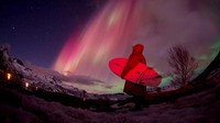 Seorang peselancar terpaku mengagumi keindahan aurora borealis yang mewarnai langit Pantai Unstad, Kepulauan Lofoten, Kutub Utara (Foto: AFP PHOTO / OLIVIER MORIN)