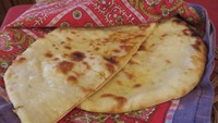 Garlic Naan bertekstur empuk renyah dengan aroma panggangan enak sisa pembakaran di tandoor. Bagian dalamnya diisi potongan bawang putih dan bawang bombay. Rasa bawang begitu dominan.