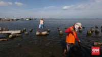 Petugas kebersihan juga memindahkan sampah-sampah dari pinggir laut ke dalam kapal sampah di Pelabuhan Kali Adem, Jakarta Utara, Senin,(2/1/2017). CNN Indonesia/Safir Makki
