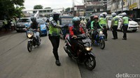 Polisi menghentikan pengendara yang melintas. Jika melanggar lalu lintas, para pengendara tersebut akan ditilang.