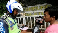 Polisi menilang pengendara yang melanggar lalu lintas.