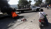 Truk dan motor melintas di samping ban bekas yang dibakar warga. Edgard Garrido/Reuters/detikFoto.