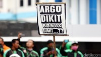 Driver GrabBike membawa poster bertuliskan Argo Dikit, Bonus Rumit.