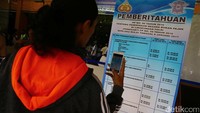 Seorang warga mengabadikan banner berisi pengumuman tentang kenaikan biaya pengurusan STNK dan BPKB.