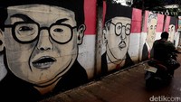 Seorang pemotor melintas di depan lukisan mural para presiden Indonesia.