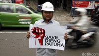 Seorang pegawai PT Geo Dipa Energi membentangkan poster bertuliskan Save Dieng Patuha.