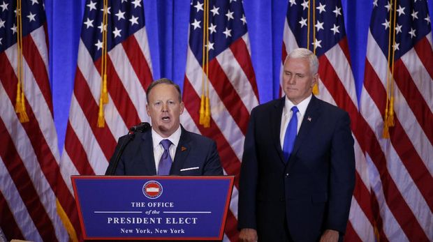 Sean Spicer (kiri) sedang berbicara di podium didampingi Wapres terpilih Mike Pence